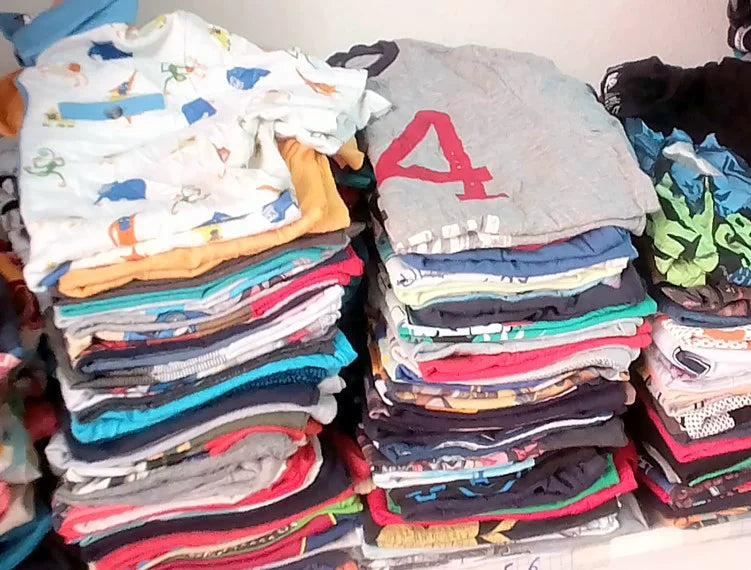 Piles de vêtements pliés, comprenant des hauts aux motifs, rayures et couleurs variés