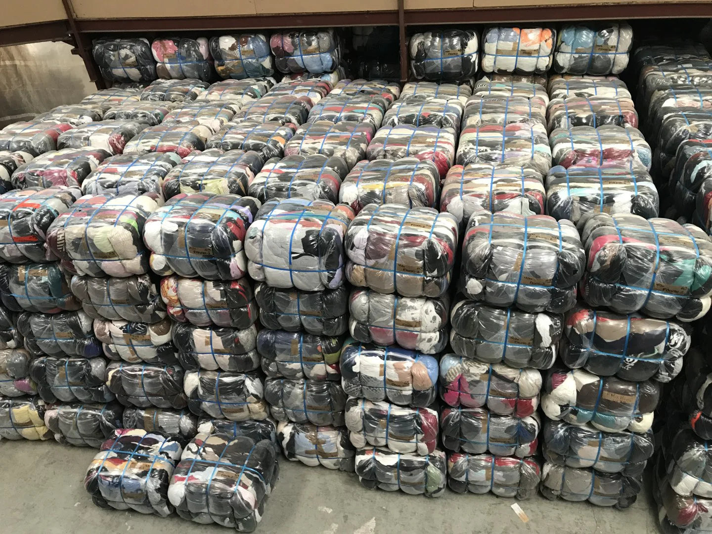 Balles de vêtements compressées et emballées dans un entrepôt, illustrant des lots de friperie en gros pour e-shop.