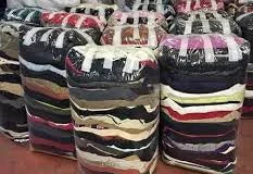 Plusieurs lots de textiles pliés ou roulés, emballés dans du plastique transparent et disposés en rangées.